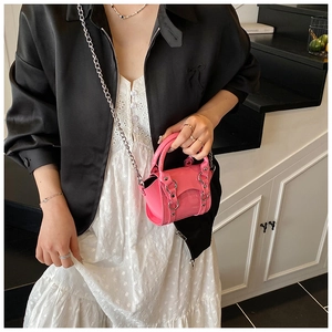Pink glossy patent leather mini bag with silver ring clasp and chain strap on a model