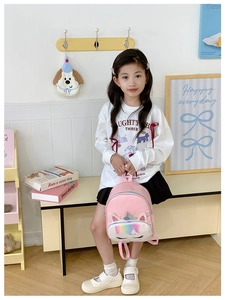 Detail of cute pink unicorn kids backpack with rainbow stripes and embroidery details