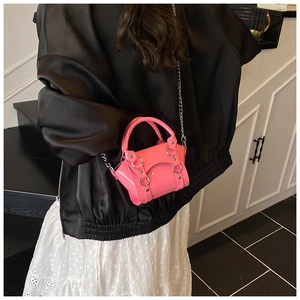 Detail of mini bright pink patent leather handbag with silver chain and metal rings