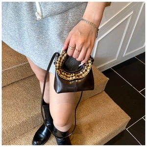Detail of mini dark brown leather handbag with yellow-brown plaid ruffle trim decor