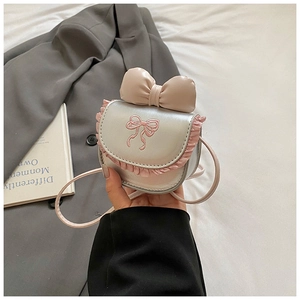 Detail of silver metallic kids crossbody bag with pink bow embroidery and ruffled trim