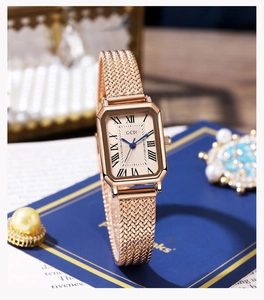 Détail d'une montre dorée vintage avec chiffres romains et aiguilles bleues sur cadran blanc