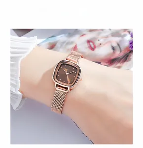Close-up of elegant square rose gold watch with brown dial on woman's wrist