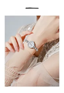 Détail de la montre de luxe avec cadran en nacre et accents de strass sur le poignet