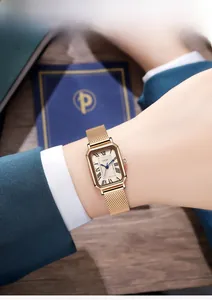 Gros plan d'une montre vintage rectangulaire dorée avec chiffres romains sur le poignet