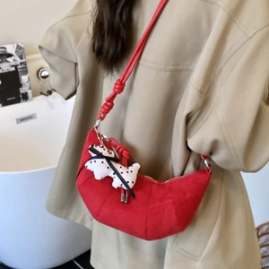 Red croissant shoulder bag for kids with a knotted strap and cute spotted dog pendant