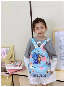 Front view of a light blue cartoon shark backpack worn by a girl in a cozy room