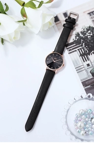 Primo piano di orologio in pelle nera con cassa oro rosa e indici in cristallo