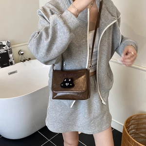 Cute dark brown leather crossbody bag with purple lettering and plush cat charm