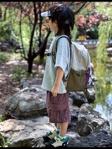 Outdoor shot showing side view of color-block kids backpack with multi-pocket cargo shorts