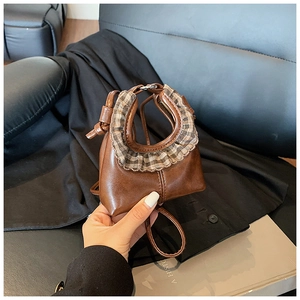 Detail of mini brown faux leather bag with stylish checkered ruffle handle and slim strap
