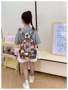 Rear view of a child wearing the cute cartoon print backpack with brown leather finish