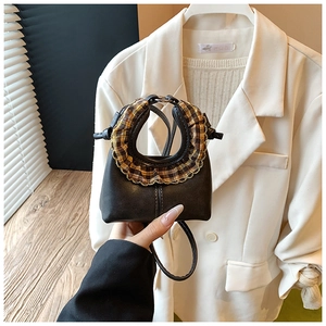 Close-up of mini round handbag featuring plaid ruffle edge and scalloped handle details