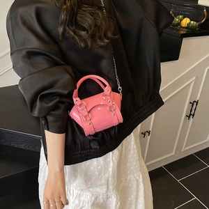 Pink patent leather mini handbag with silver studs and chain strap shown on a model