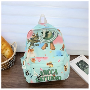 Detail of light blue backpack with surreal art print and VACCA SATURNO logo on a desk