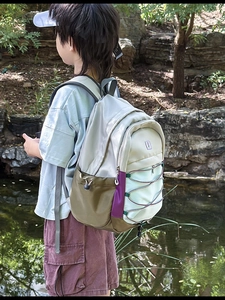 Detail of color-block nylon kids backpack with elastic cords and side pockets in nature