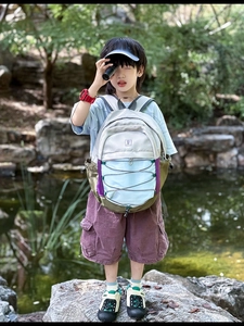 Detail of colorful outdoor kids backpack featuring elastic cords and durable multi-panel fabric