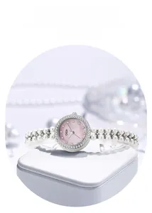 Détail du cadran en nacre rose et du bracelet à double rangée de perles de la montre