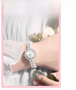 Vue macro du cadran en nacre avec lunette en cristal et bracelet élégant en perles