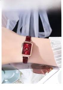 Nahaufnahme der quadratischen Roségold-Uhr mit weinrotem Zifferblatt und Lederarmband