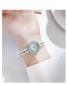 Vue macro d'une montre bracelet en perles avec cadran en nacre bleue et cristaux brillants