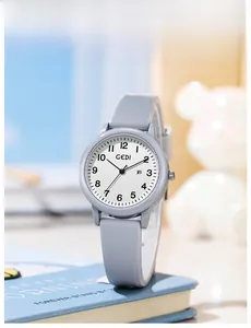 Macro shot of grey quartz watch with silicone strap and date display on a blue book