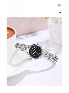 Elegant silver bracelet watch with black Roman dial placed on a ceramic coffee saucer