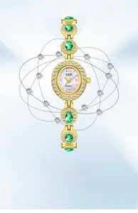 Detail of luxury gold bracelet watch with emerald stones and diamond-set oval dial