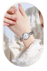 Detail of silver chain watch with white Roman dial and blue hands on female wrist