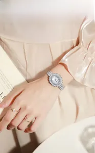 Close-up of silver sunflower watch with cubic zirconia and metal mesh strap on wrist