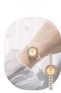Détail d'une montre en or rose avec strass brillants et bracelet de perles à double rangée
