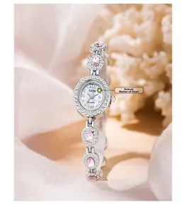 Close-up of oval quartz watch with natural mother-of-pearl dial and pink gemstones