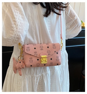 Sac enveloppe rose à imprimé chat et fermoir doré sur une robe plissée blanche