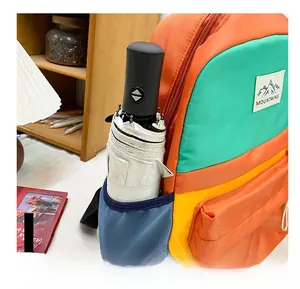 Detail of multi-color children backpack side pocket holding a white folding umbrella