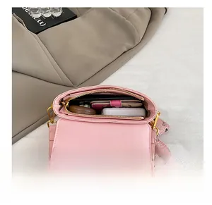 Vue intérieure d'un sac bandoulière rose montrant le rangement et zip doré