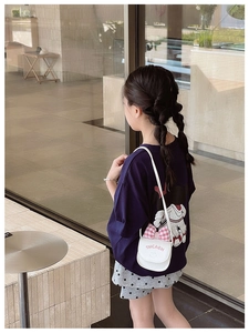Detailed view of mini white crossbody bag with pink bow and letters on a child outfit
