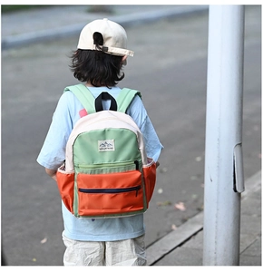 Rear view of vibrant color-block school backpack with Mountains badge on outdoor street
