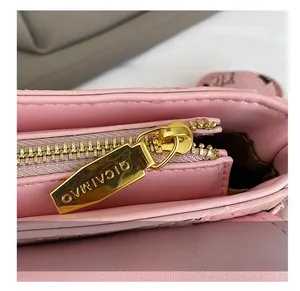 Gros plan détaillé sur la fermeture éclair en métal doré et le cuir rose du sac à main