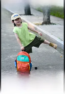 Outdoor close-up of a vibrant color-block kids backpack with orange and green panels