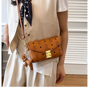Détail d'un sac bandoulière en cuir marron avec imprimés chats et breloque chiot