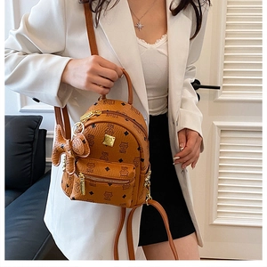 Detail of caramel brown backpack with all-over cat print and gold metal logo plaque