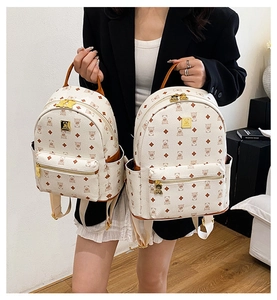 Detail showing two sizes of cream white backpacks with cute bear print and golden zippers