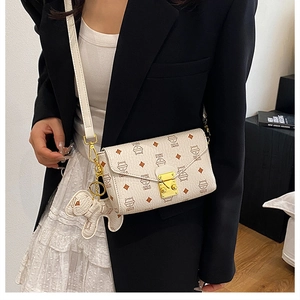 Vue détaillée du sac bandoulière crème avec imprimés chats et breloque 3D sur un mannequin