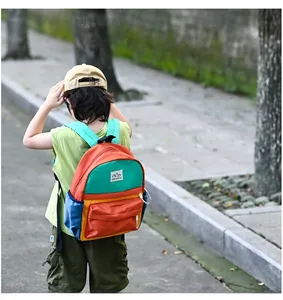 Kids colorful waterproof nylon backpack with MOUNTAINS logo shown on child's back
