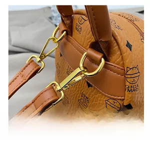 Detail of the golden metal strap hook on a brown litchi grain leather backpack
