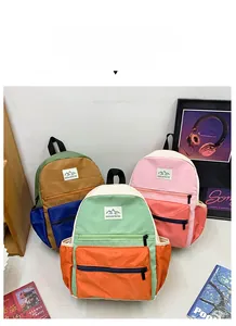 Detail of color-block nylon backpacks with front zipper pockets and mountain peak labels