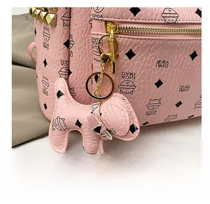 Détails d'un sac à dos rose en cuir grainé avec pendentif chat et fermetures dorées