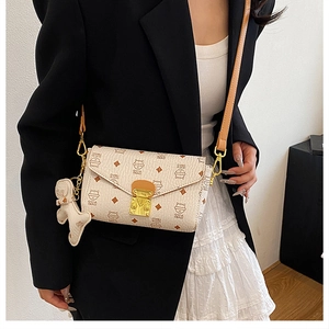 Sac enveloppe beige à motif chat et breloque ours, porté par un mannequin pour le style