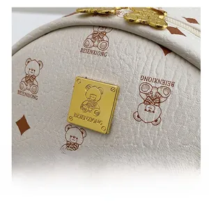 Close-up of white lychee leather texture with cute bear print and golden hardware