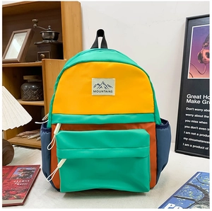 Detail of color-block school backpack with MOUNTAINS logo and durable nylon fabric texture
